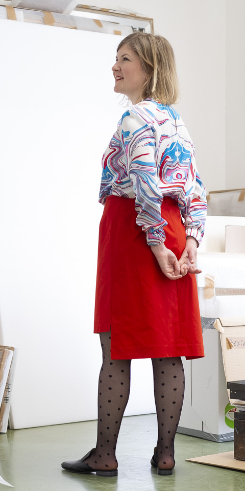 Bluse aus Seidensatin mit abstraktem Print und Rock aus tomatenrotem Baumwollgabardine, Rückansicht